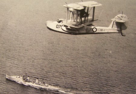 Sydney’s Walrus aircraft flying over the cruiser.